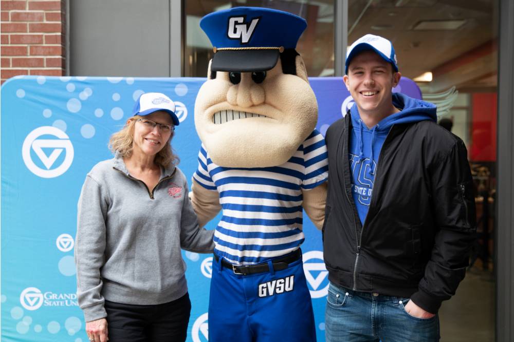 Two alumni pose with Louie the Laker at the Detroit Red Wings GVSU Night
